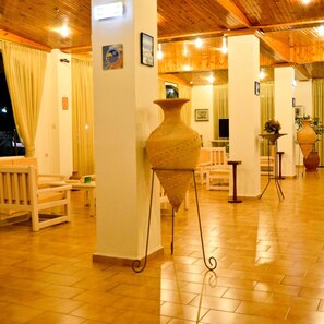 A room with wooden flooring, a large vase on a pedestal, and a bed with a headboard. - Niko Elen Hotel (Hersonissos)