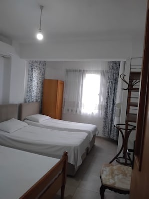 A hotel room with two beds, a wardrobe, a chair, and a desk. - Özler Apart Pansiyon (Edremit)