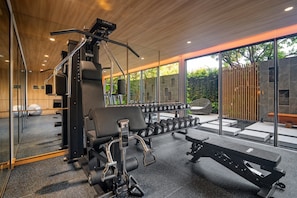 A modern gym with weightlifting equipment, dumbbells, and exercise benches. - Seashore Residences, Three-Bedroom 3B Deluxe (Thalang)