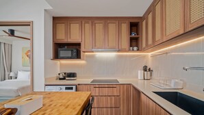 A modern kitchen with wooden cabinets, a microwave, a coffee maker, and a sink. - Seashore Residences, Three-Bedroom 3A Premium (Thalang)