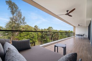 Ein Balkon mit einer Couch, einem kleinen Tisch und einem Deckenventilator.