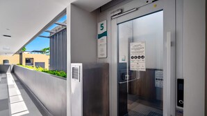 A modern elevator with a glass door, a number 5 sign, and a safety information sign. - Seashore Residences, Three-Bedroom 3A Premium (Thalang)