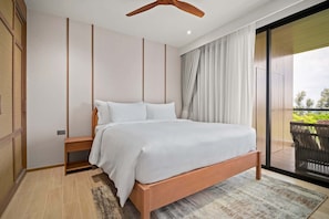 A modern bedroom with a wooden bed, a small bedside table, and a large window with curtains. - Seashore Residences, Three-Bedroom 3B Premium (Thalang)
