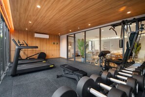 A gym with exercise equipment, a treadmill, dumbbells, and a bench. - Seashore Residences, Three-Bedroom 3B Premium (Thalang)