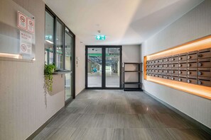 A modern hotel lobby with a glass door entrance, a wall-mounted plant, and a wooden panel display. - Seashore Residences, Three-Bedroom 3B Premium (Thalang)