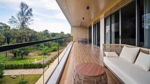 Een balkon met een houten vloer, een ronde tafel en een bank met kussens.