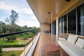 A balcony with a wooden floor, a round table, and a sofa with cushions. - Seashore Residences, Three-Bedroom 3B Premium (Thalang)