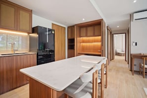Eine moderne Küche mit Holzschränken, einem schwarzen Kühlschrank und einer Marmorarbeitsplatte.