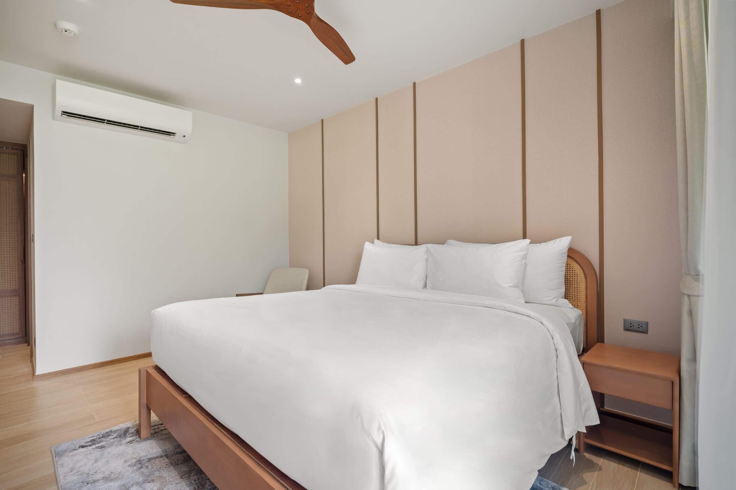 A modern bedroom with a bed, bedside table, and a ceiling fan.