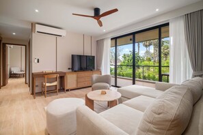 Ein modernes Wohnzimmer mit einer Couch, einem runden Couchtisch, einem Fernseher und einem Schreibtisch.