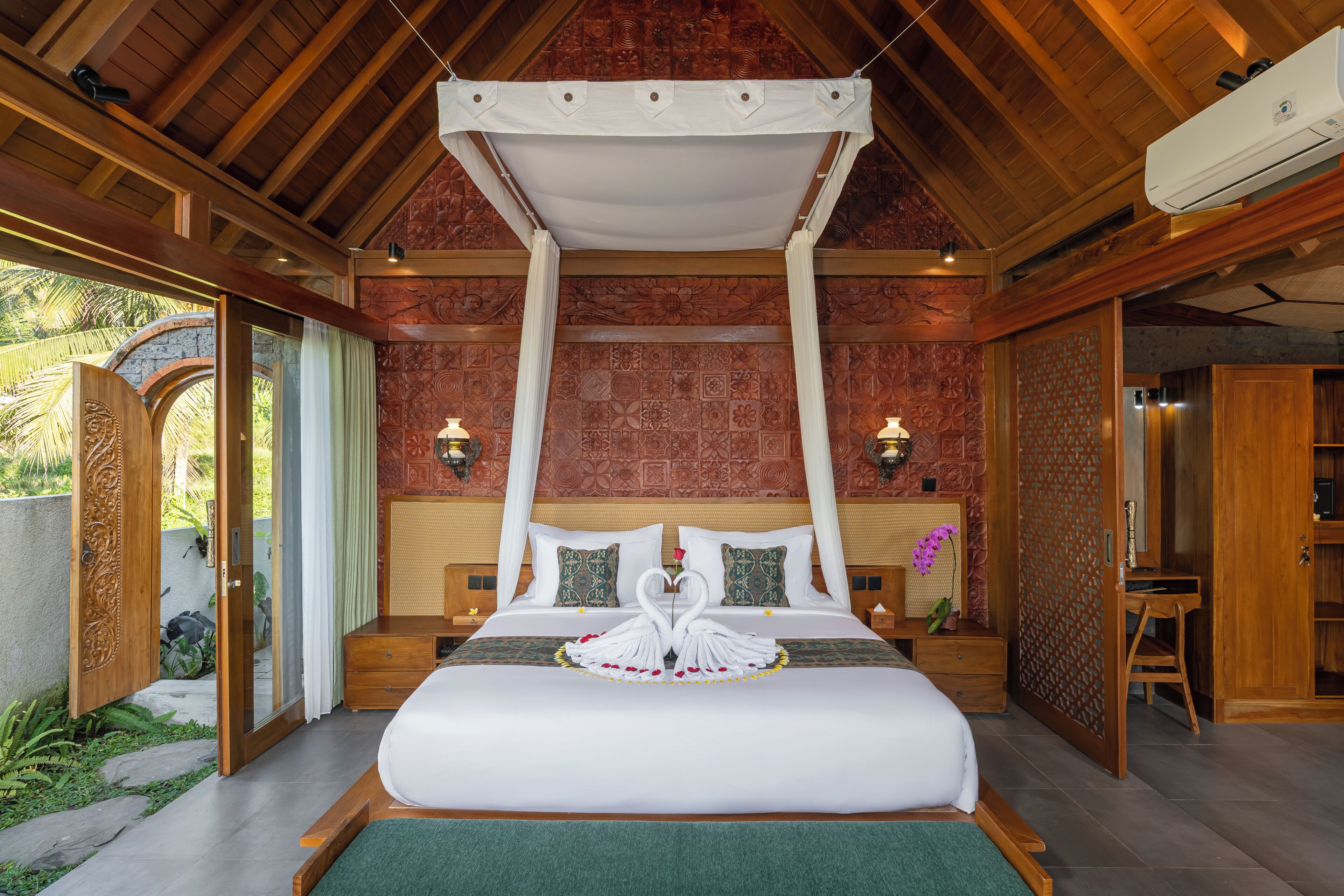 A room with a bed, a canopy, a nightstand, a lamp, and a view of the outdoors.