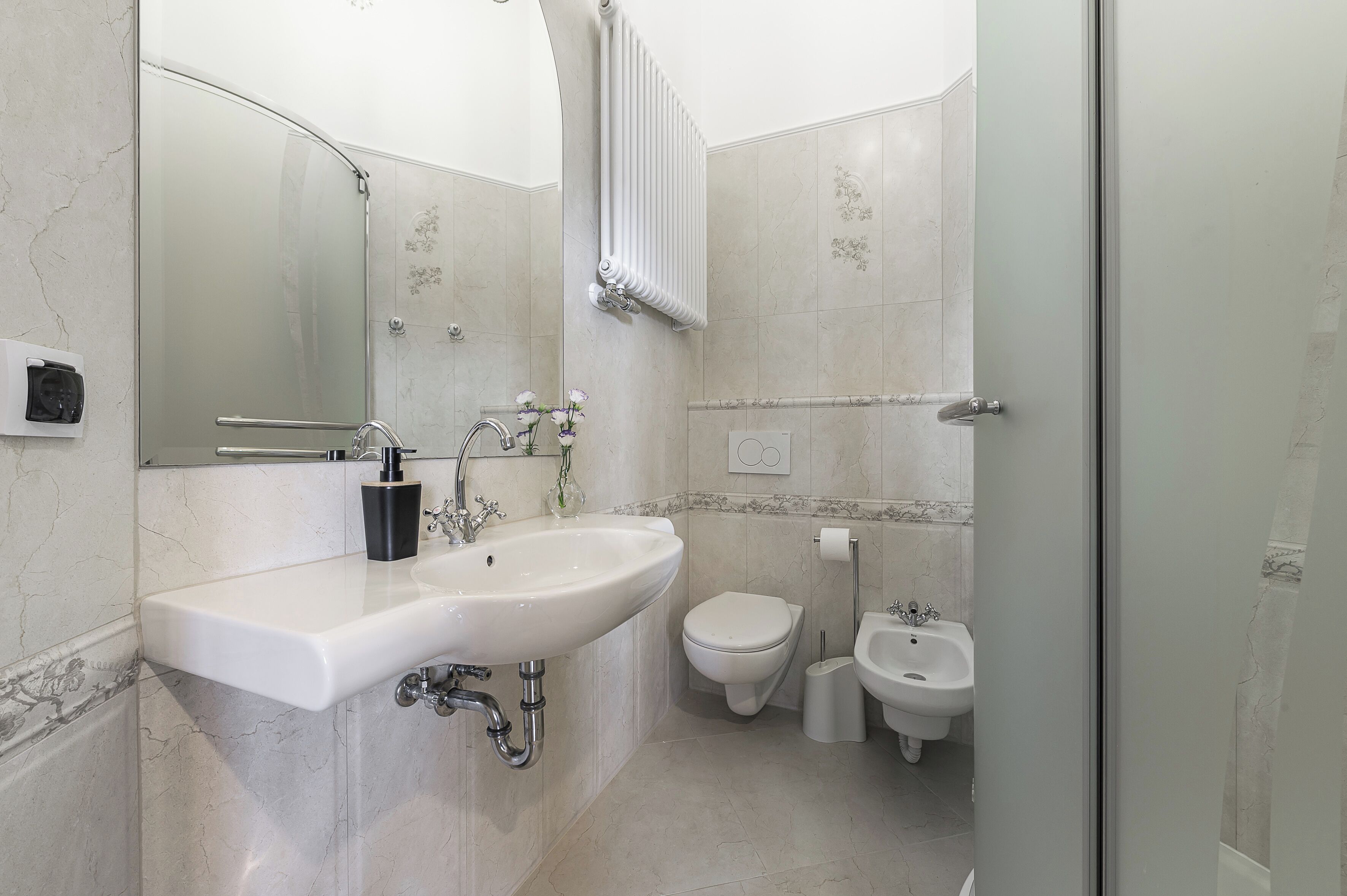 A bathroom with a sink, toilet, bidet, and a mirror.