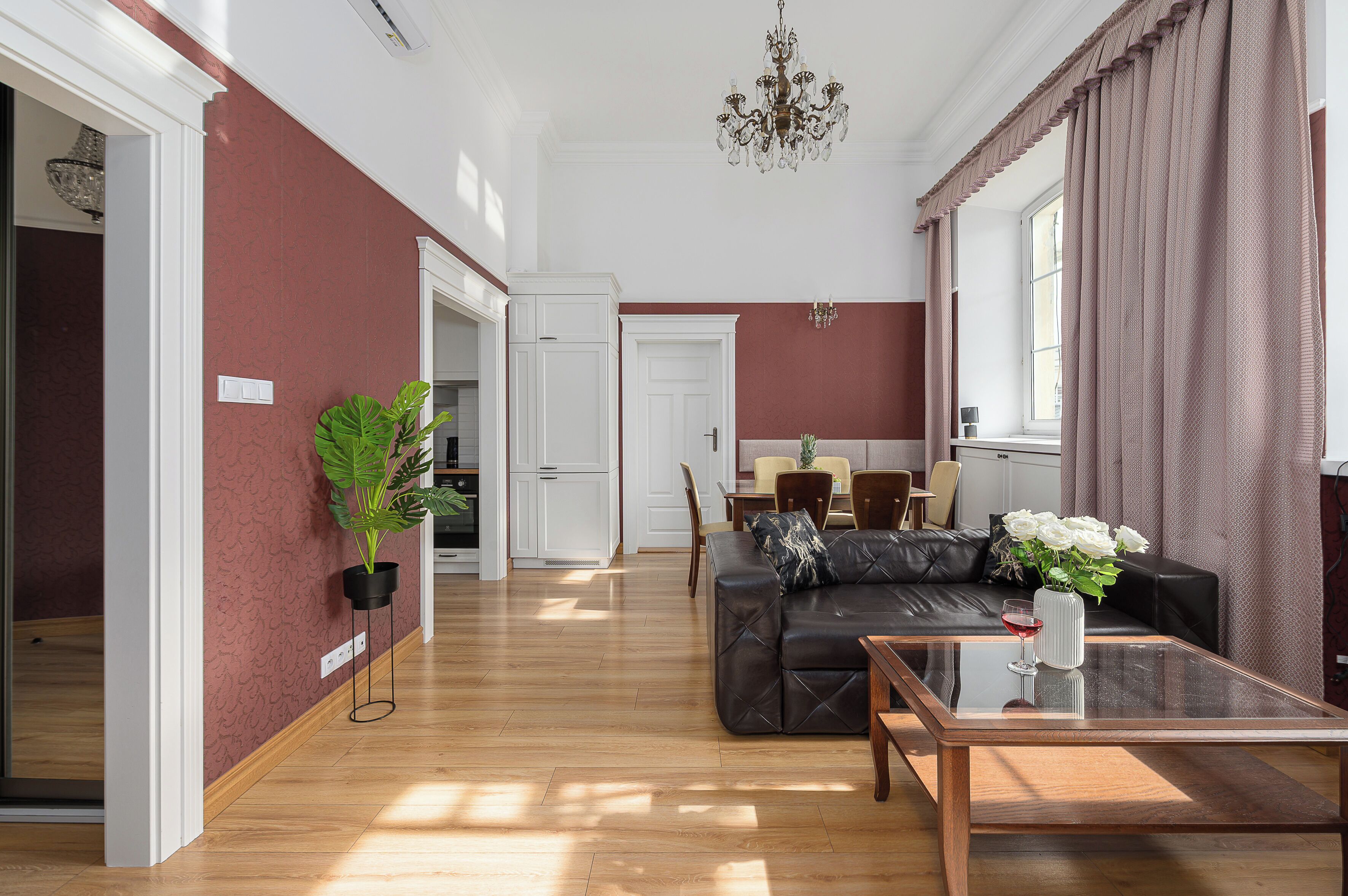 A spacious living area with a dark leather sofa, a glass coffee table, and a dining area with a table and chairs.