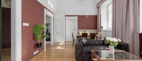 A spacious living area with a dark leather sofa, a glass coffee table, and a dining area with a table and chairs.