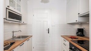 Une cuisine moderne avec des meubles blancs, un four à micro-ondes, un évier et une machine à café.