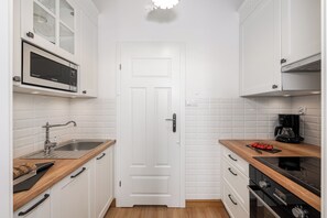 Eine moderne Küche mit weißen Schränken, einer Mikrowelle, einem Spülbecken und einer Kaffeemaschine.