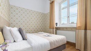 Un lit bien fait, avec un matelas gris et du linge de lit blanc, une lampe de chevet et un livre posé sur la table de chevet.
