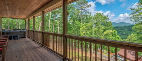 Una terraza de madera con vistas a un bosque y montañas.