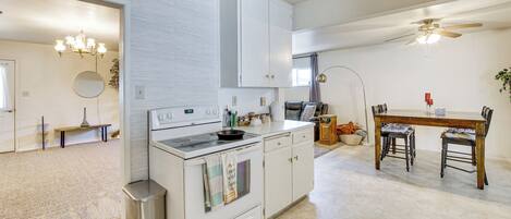 A kitchen with white cabinetry, a stove, and a dining area with a table and chairs.