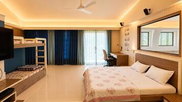 A hotel room with a bed, a desk, a TV, a ceiling fan, and a window with curtains.