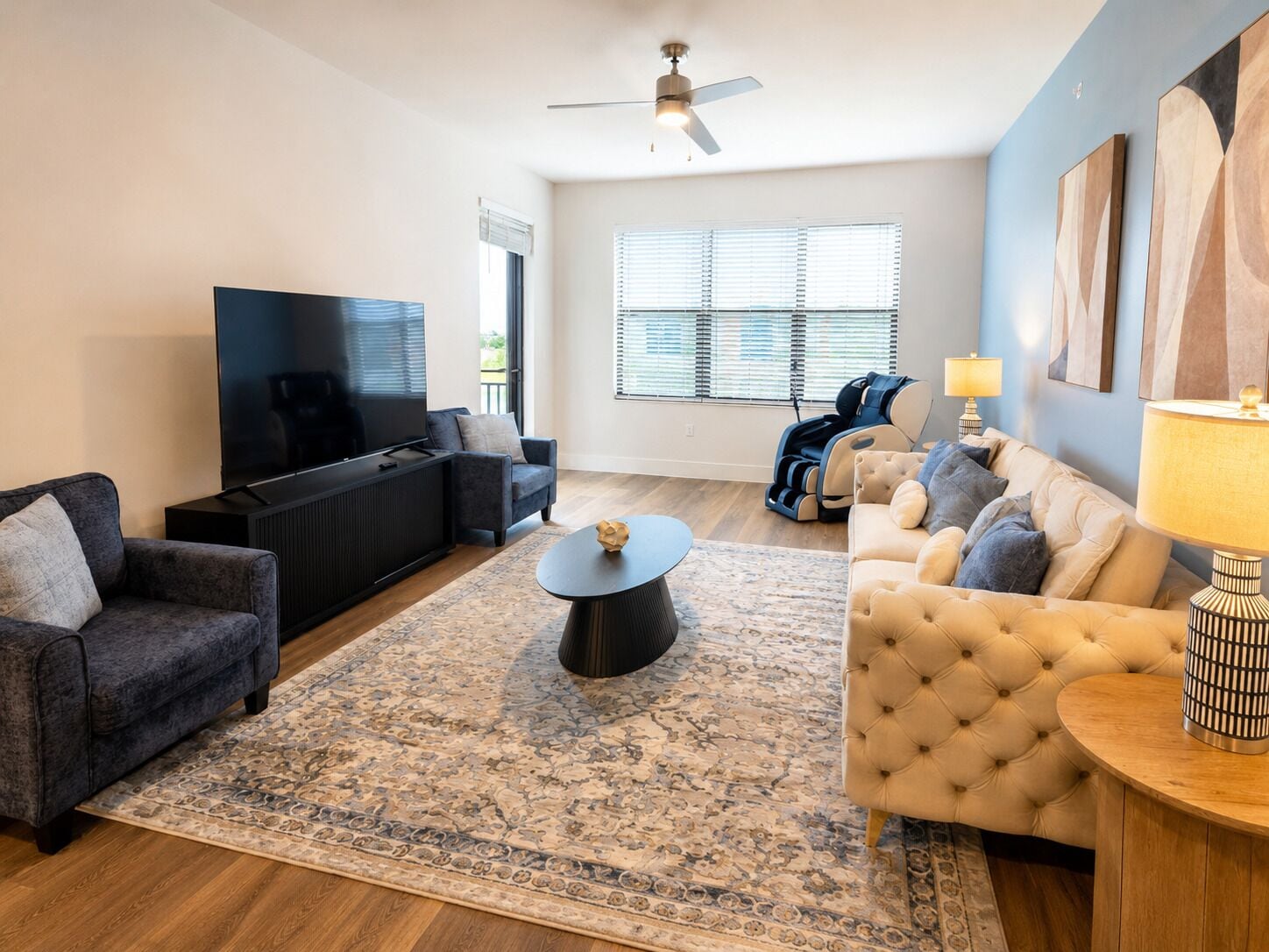 Un salon moderne doté d’un téléviseur à écran plat, de deux canapés, d’une table basse et d’un ventilateur de plafond.