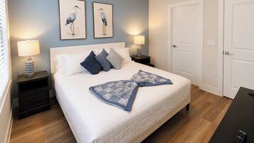 A bedroom with a bed, two nightstands, two wall-mounted lamps, a door, and a remote control on a table.