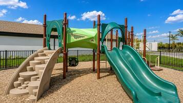 A playground with a slide, climbing steps, and a green climbing structure.