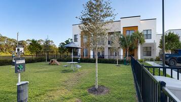 A well-maintained grassy area with a picnic table, a trash can, and a dog waste station.