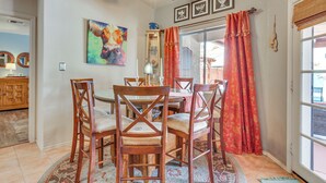 Een eethoek met een tafel, stoelen, een plafondventilator en een raam met gordijnen.