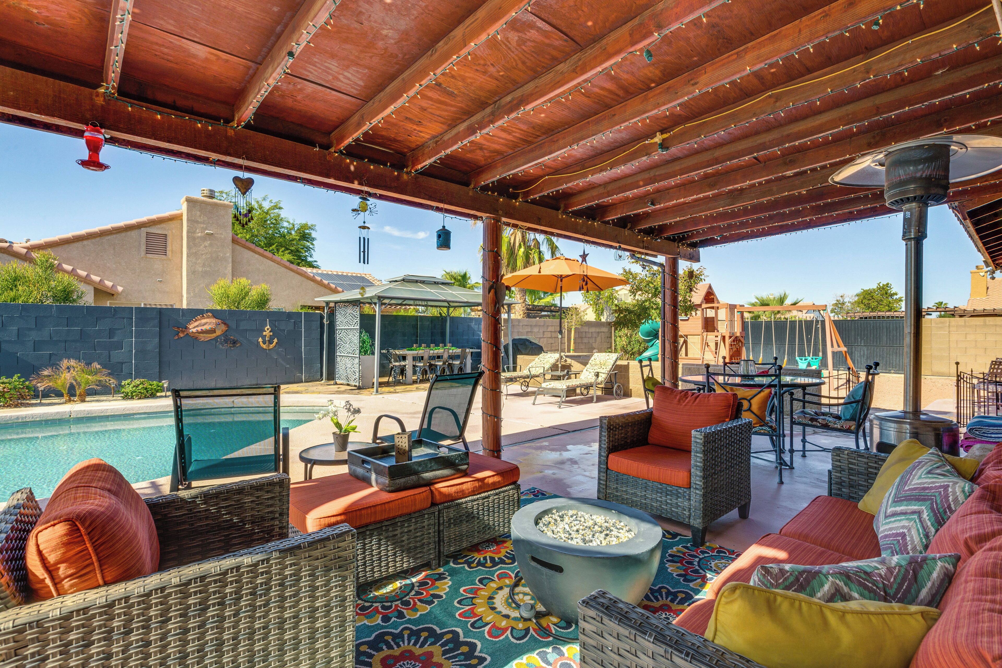 Un patio al aire libre con mobiliario de mimbre, una piscina y una zona de barbacoa.