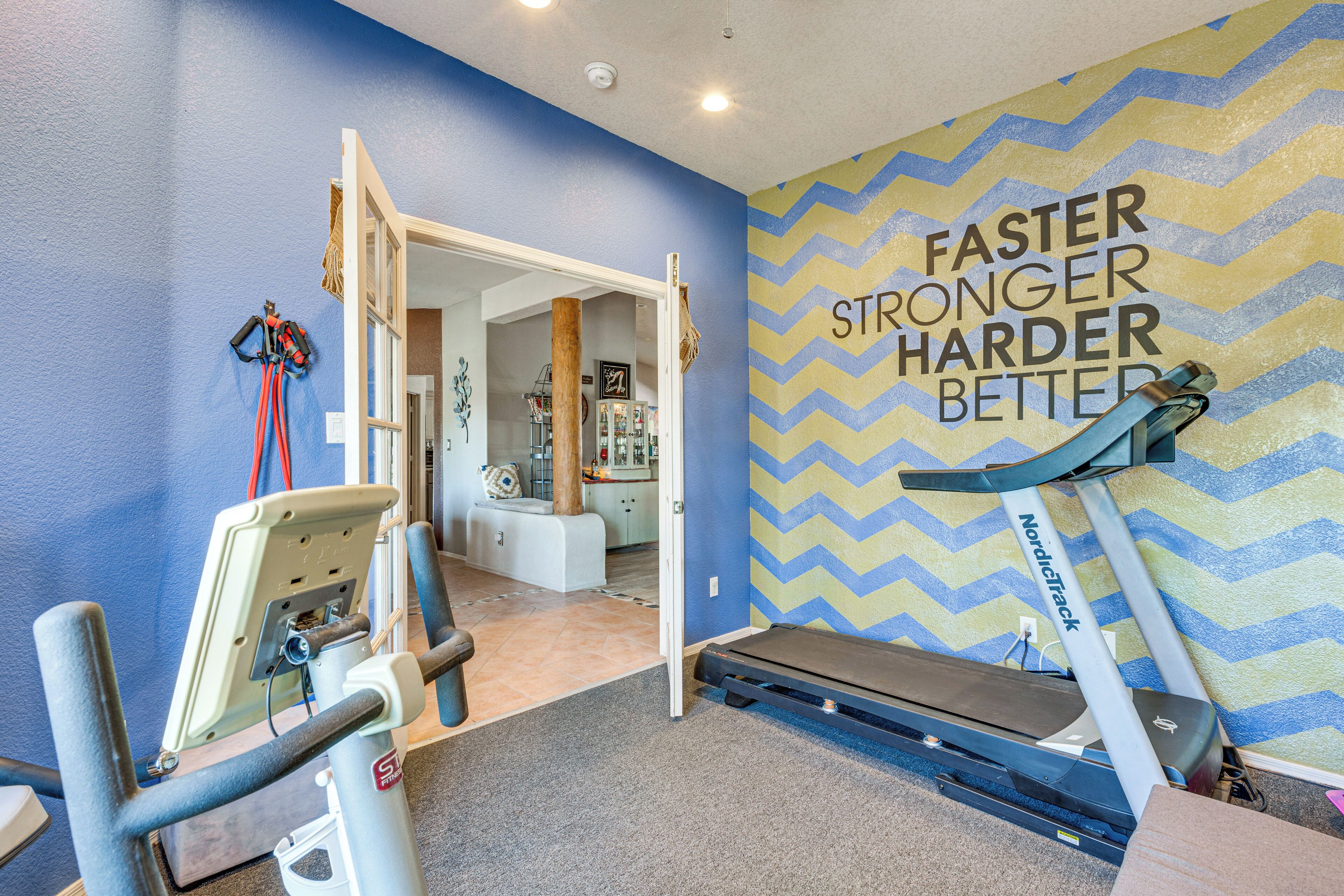 A fitness room with exercise equipment, a treadmill, and a motivational wall.