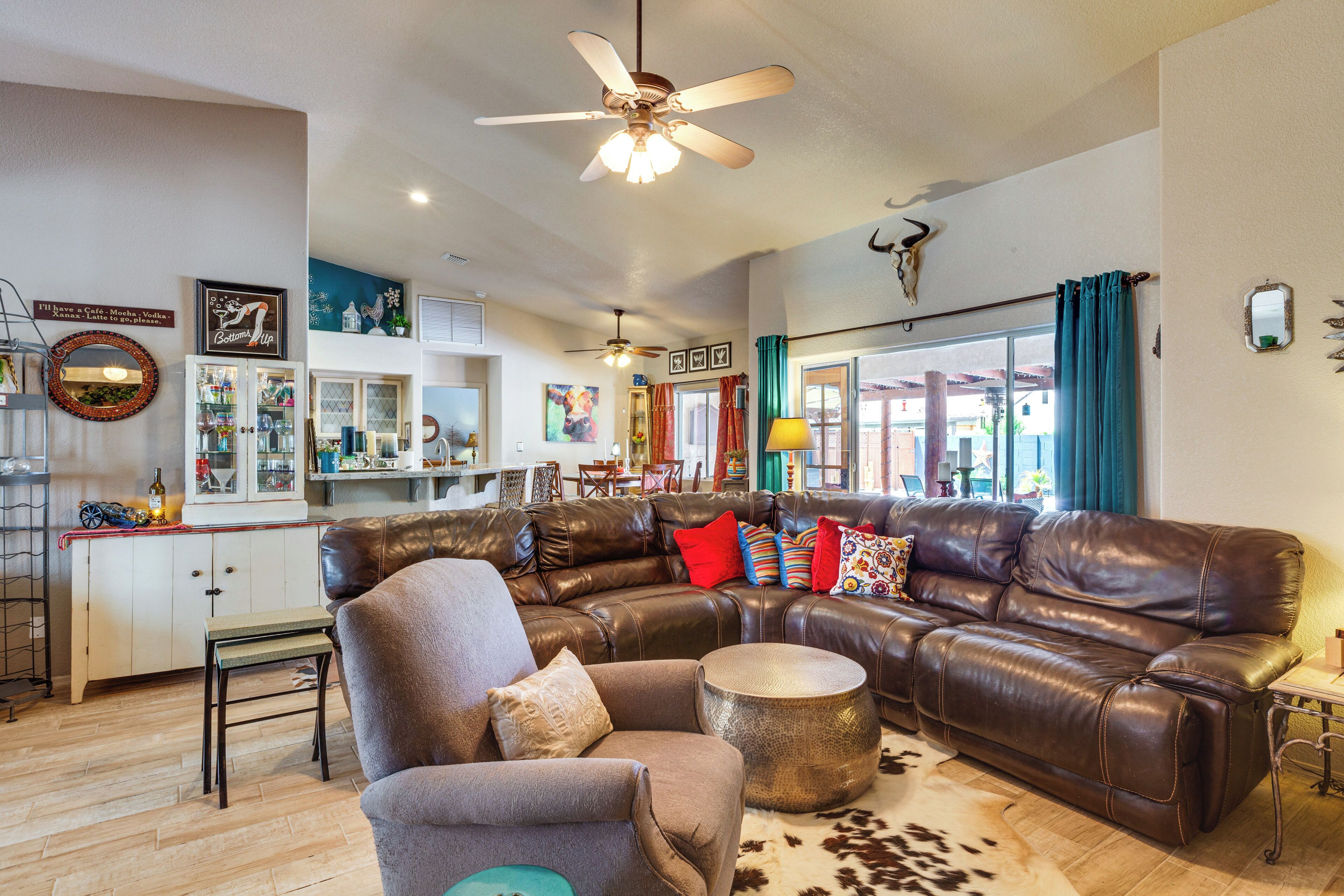 Ein Wohnzimmer mit einem braunen Ledersofa, einem grauen Sessel und einem runden Couchtisch auf einem Kuhfellteppich.