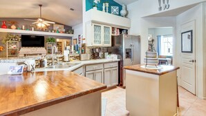 Een moderne keuken met een groot eiland, roestvrijstalen apparatuur en diverse decoratieve objecten.