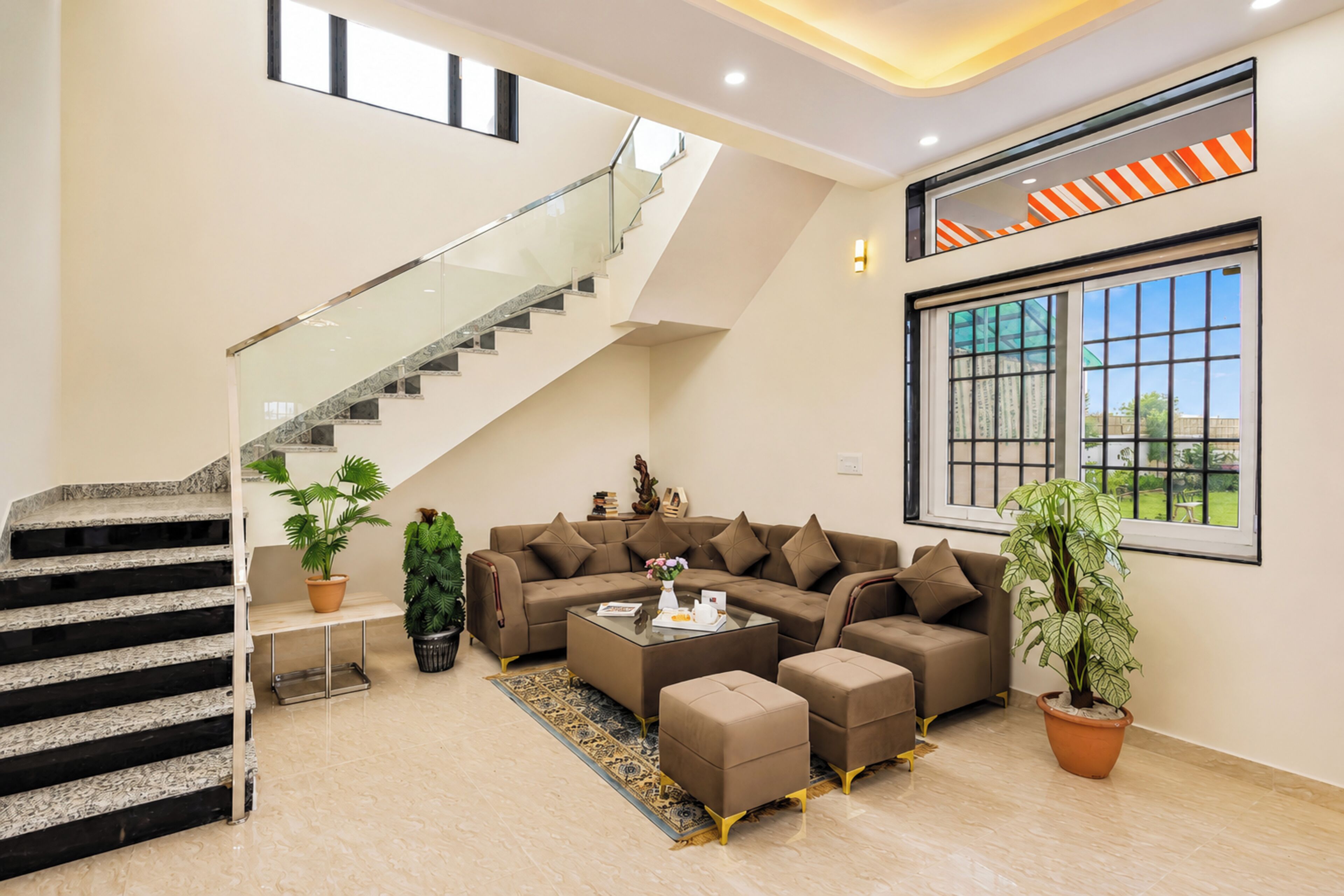 A spacious living area with a modern staircase, a large window with a view, and a comfortable seating arrangement.