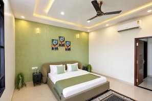 A modern bedroom with a bed, nightstands, a ceiling fan, wall-mounted air conditioning, and decorative wall art.