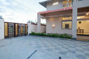 A modern house with a gated entrance, a covered porch, and a well-maintained garden.