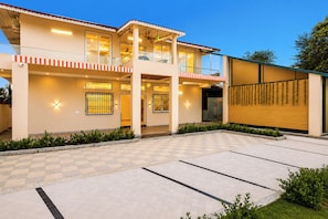 A two-story building with a balcony, a covered entrance, and a checkered driveway.