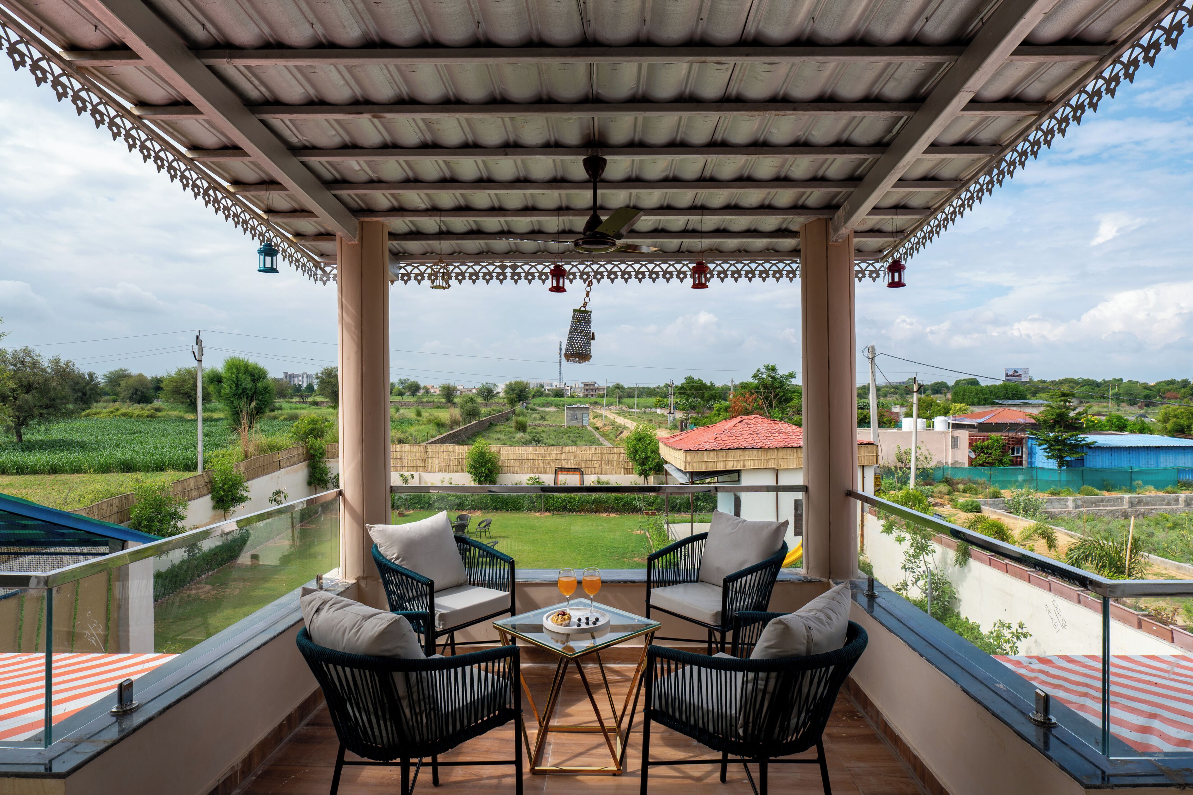 Un balcon avec deux chaises et une table, donnant sur un paysage rural composé de champs et de maisons.