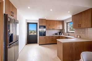 A modern kitchen with wooden cabinets, a built-in oven, and a refrigerator. - Villa Vision | Brand New, Private Pool & Seaviews (Chania)