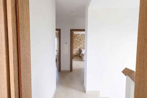 A hallway with a stone wall and a bed in the distance. - Villa Vision | Brand New, Private Pool & Seaviews (Chania)