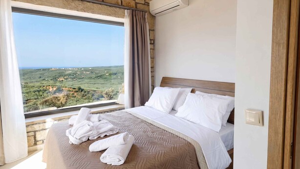 A hotel room with a large bed, a view of the countryside, and an air conditioning unit. - Villa Vision | Brand New, Private Pool & Seaviews (Chania)