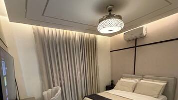 A modern bedroom with a bed, a desk, a chair, and a television.