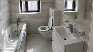 A modern bathroom with a bathtub, toilet, and vanity. - Luxury Stay in the City Center (Bucharest)