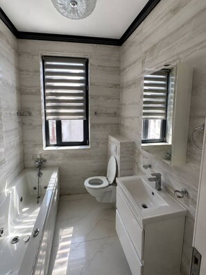 Ein modernes Badezimmer mit Badewanne, Toilette und Waschtisch.