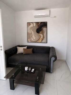 A modern living room with a dark grey sofa, a glass coffee table, and a large abstract painting on the wall. - Luxury Stay in the City Center (Bucharest)