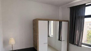 A room with a desk, chair, wardrobe, and a window with curtains. - Luxury Stay in the City Center (Bucharest)