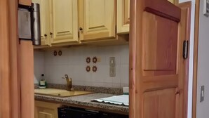 Een keuken met houten kastjes, een spoelbak, een kraan en een vaatwasser.