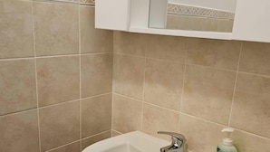 Een badkamer met een witte wasbak, een spiegel en een zeepdispenser.