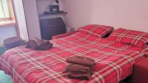 Een slaapkamer met een bed, een dressoir, een radiator en een raam.