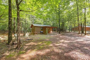 Ein rustikales Blockhaus mit Veranda, umgeben von einem Wald.